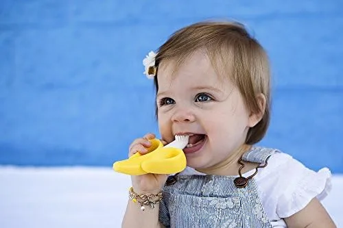 A toddler grips the flexible handle herself, the bristles reaching molars during independent practic