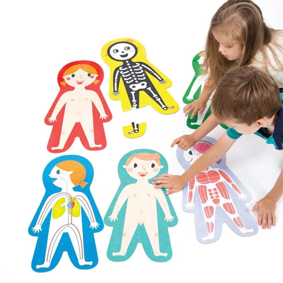 Two children assemble the floor puzzle together, sliding palm-sized pieces into anatomical positions