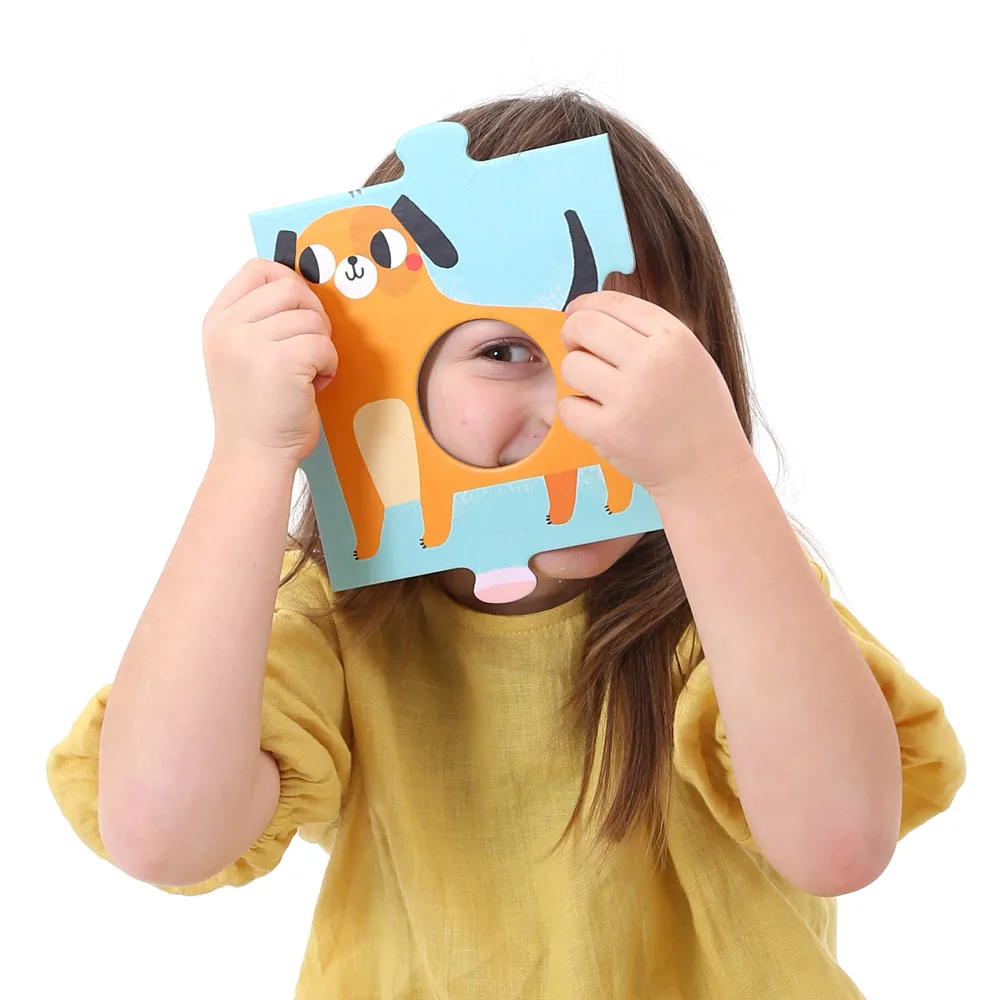 A child peers through a single puzzle piece, scale evident against her face and hands.