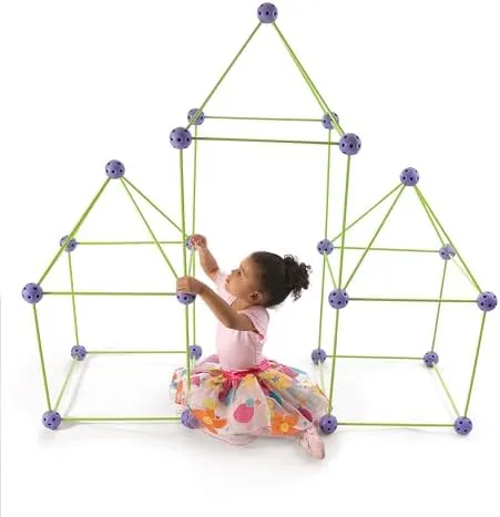 A toddler in a tutu inspects the joints of a triple-peaked castle she's helped construct.