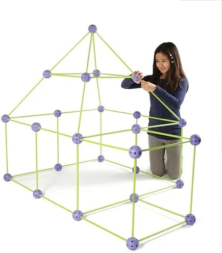 A girl adds a ridge piece to a multi-room structure roughly her own height, mid-build.