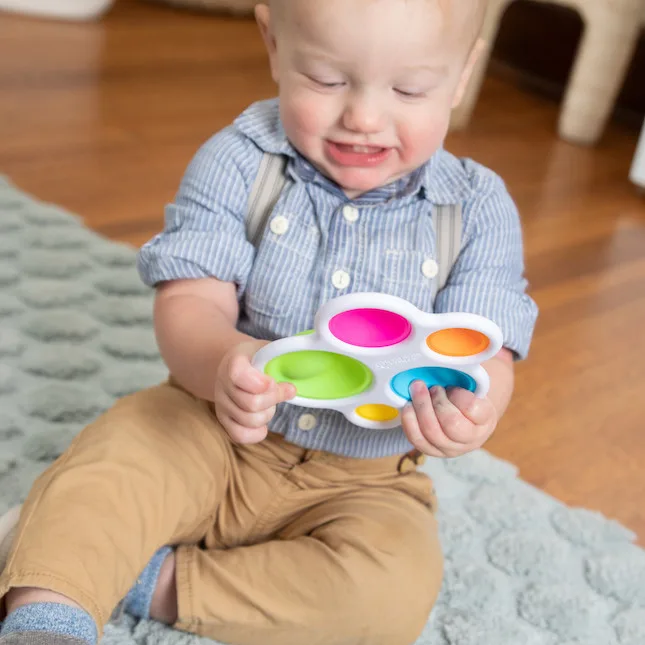 A toddler grins as he discovers the satisfying give of each colored silicone bubble.