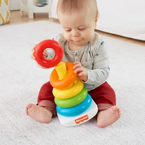 A baby studies a single ring before committing it to the post — early problem-solving made visible.