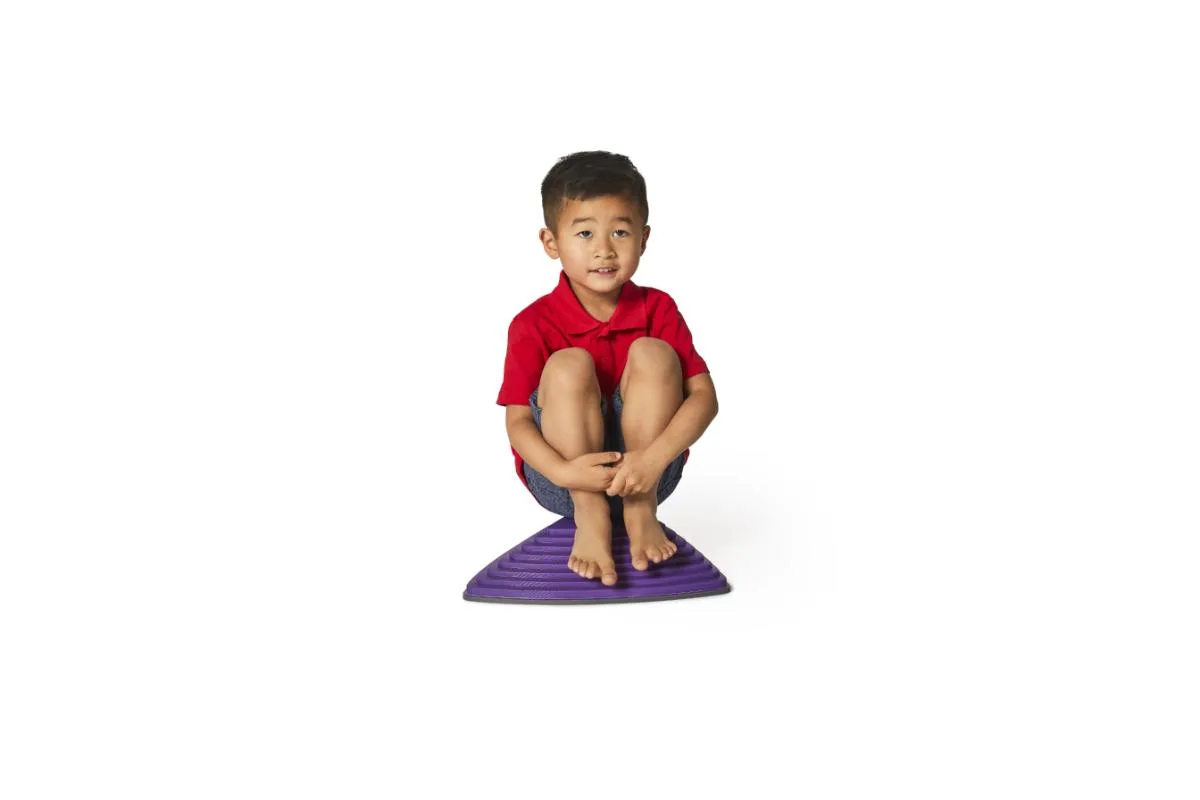 A toddler perches on a single purple stone, weight centered as he tests its stability.