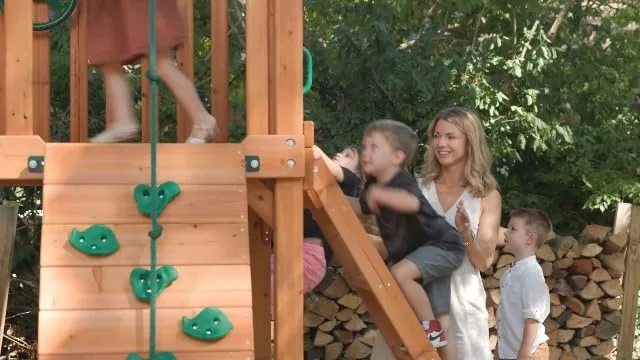 A child climbs the rock wall while siblings cheer below, the kind of unstructured risk the set invit