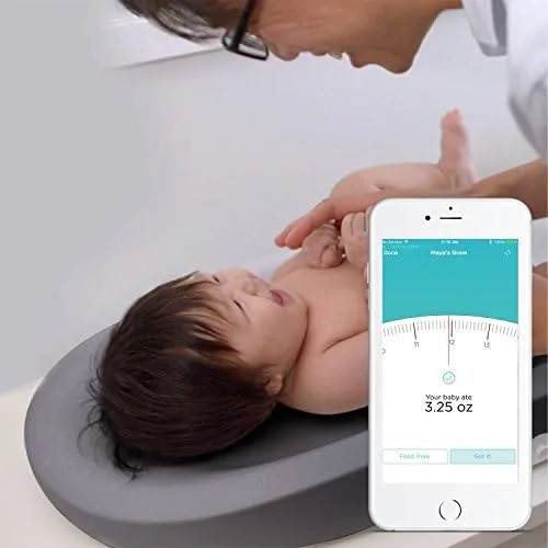 A parent logs a feeding while the baby rests on the pad's contoured surface.