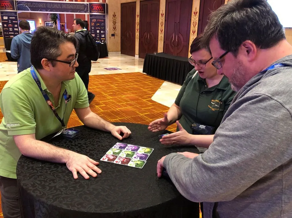Adults demoing the dance-card mechanic at a trade show — proof that the game crosses age lines.