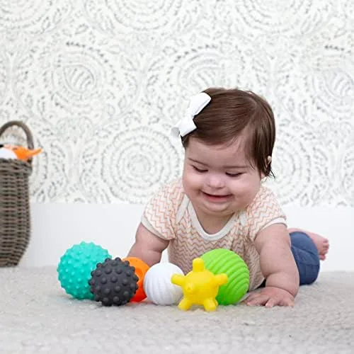 A baby grins beside the full six-ball set, each sphere a different size, color, and texture.