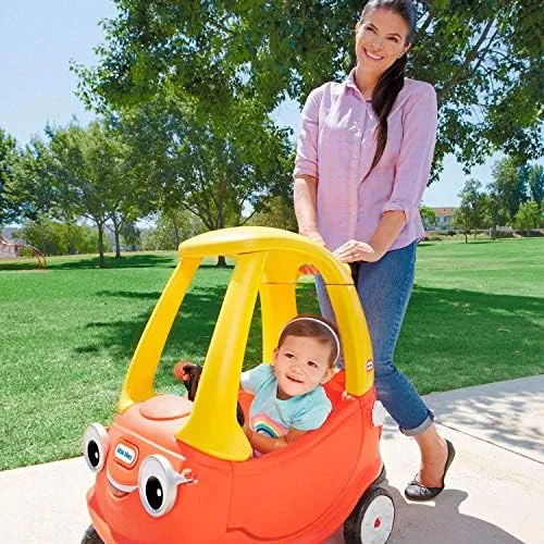 A parent uses the rear push handle to guide a younger rider, one of the Cozy Coupe's most-used featu