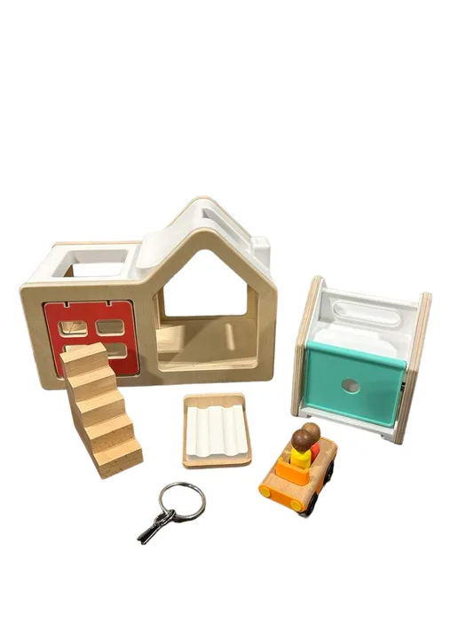 Full kit laid out — house frame, ramp, peg figures, vehicle, and signature Montessori key.