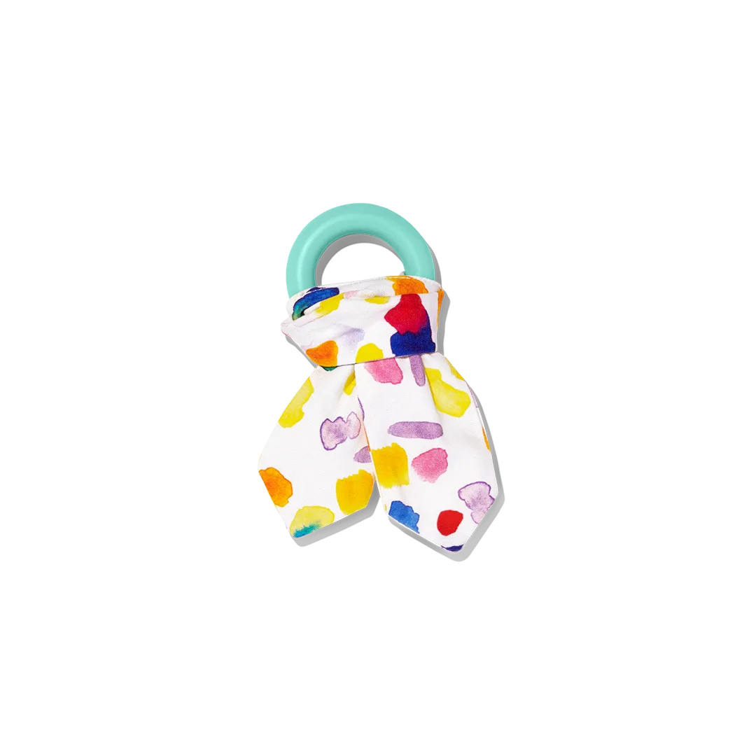 A silicone teether wrapped in printed cotton, paired for grip practice and oral exploration.