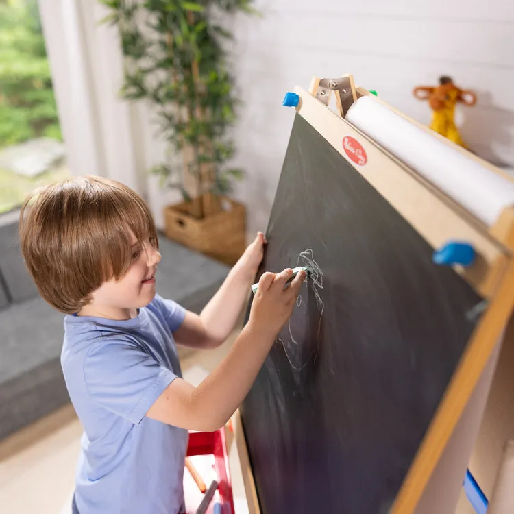 A child works at standing height, a posture that engages the shoulder rather than just the wrist.