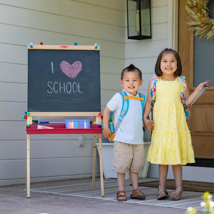 Two siblings beside the assembled easel, which folds flat for storage between sessions.