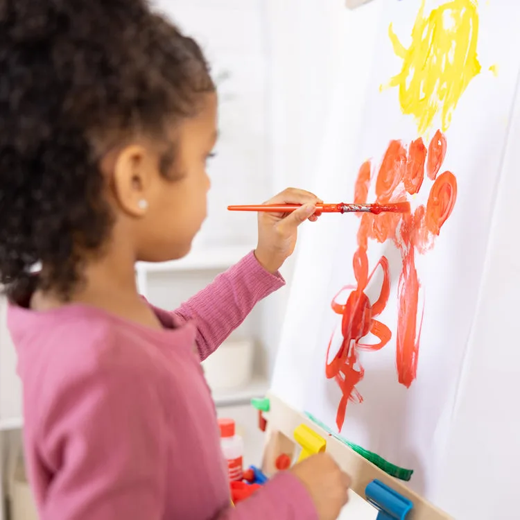 Tempera paint on butcher paper, the setup that lets a three-year-old commit fully without staining f