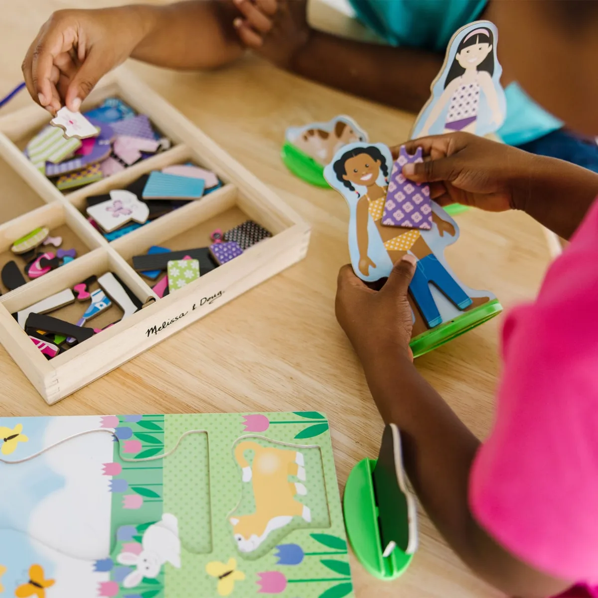 Children mid-play: hands selecting magnetic outfits, the satisfying snap-and-decide moment the revie