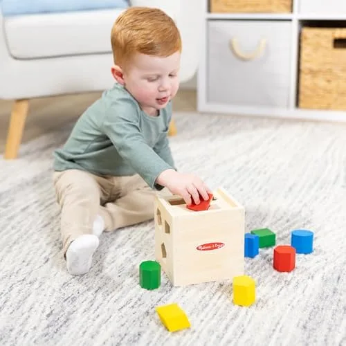 A toddler concentrates on fitting a piece through the correct opening.