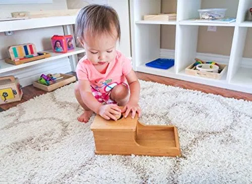 A toddler engages with the box on a rug, demonstrating the in-and-out repetition cycle.