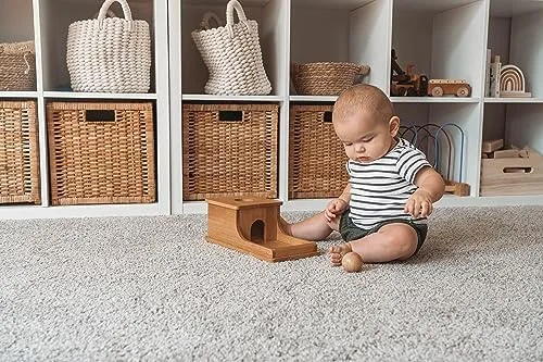 An infant works the box independently, the ball already returned to the tray.