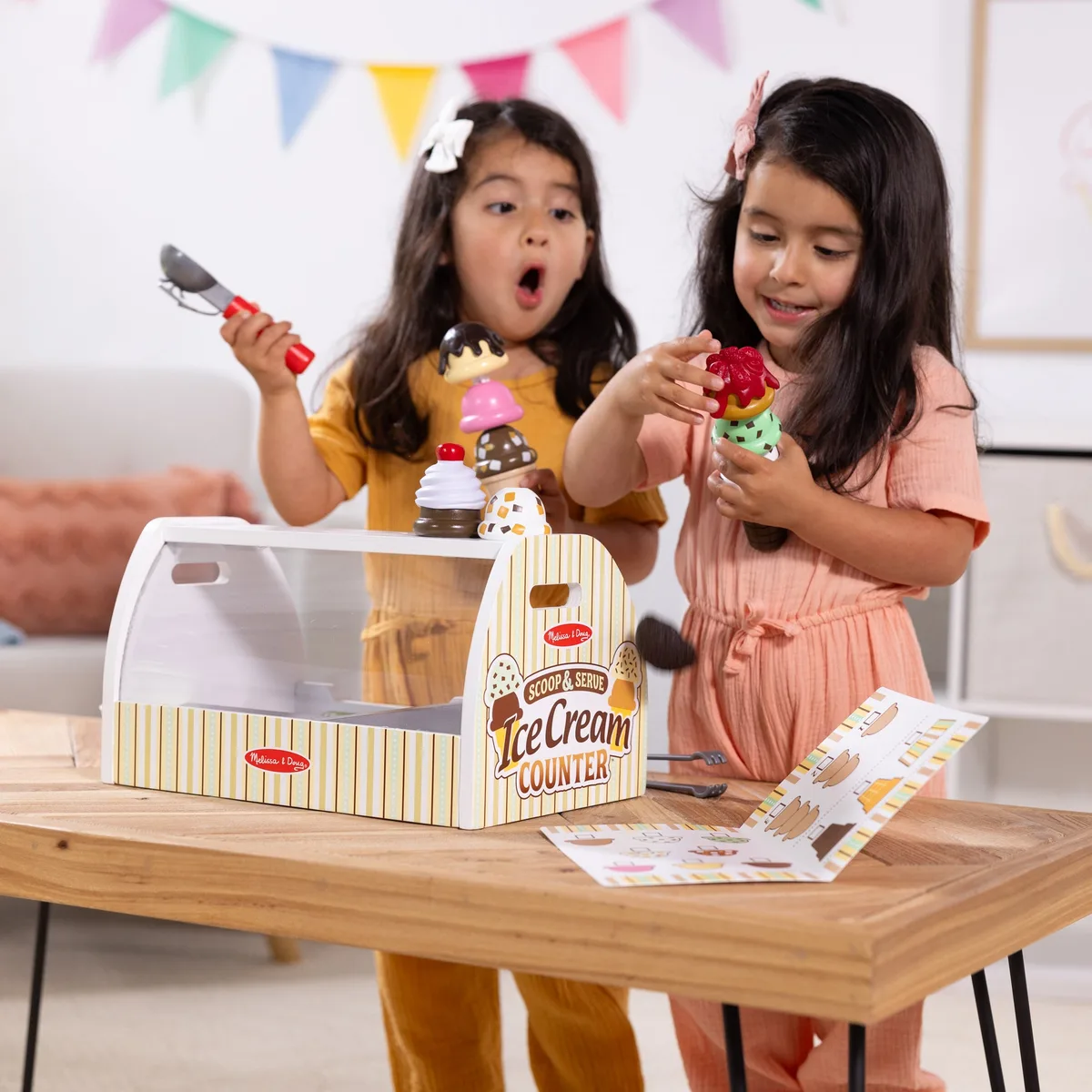 Two children negotiate roles, exchange goods, and practice the social scripts of transactional play.