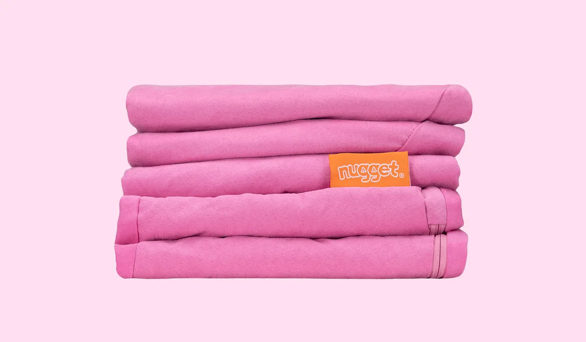 Folded covers in the Mini's signature pink microsuede — the swappable cover system parents either lo