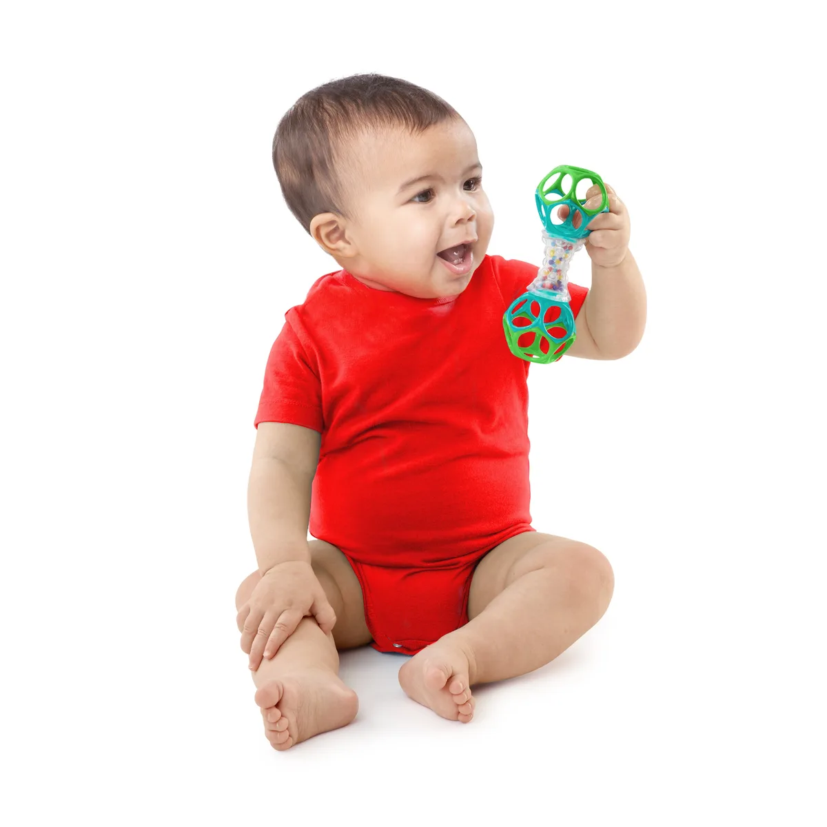 An infant grasps the Oball Shaker, demonstrating how openings accommodate even early palmar grasp.