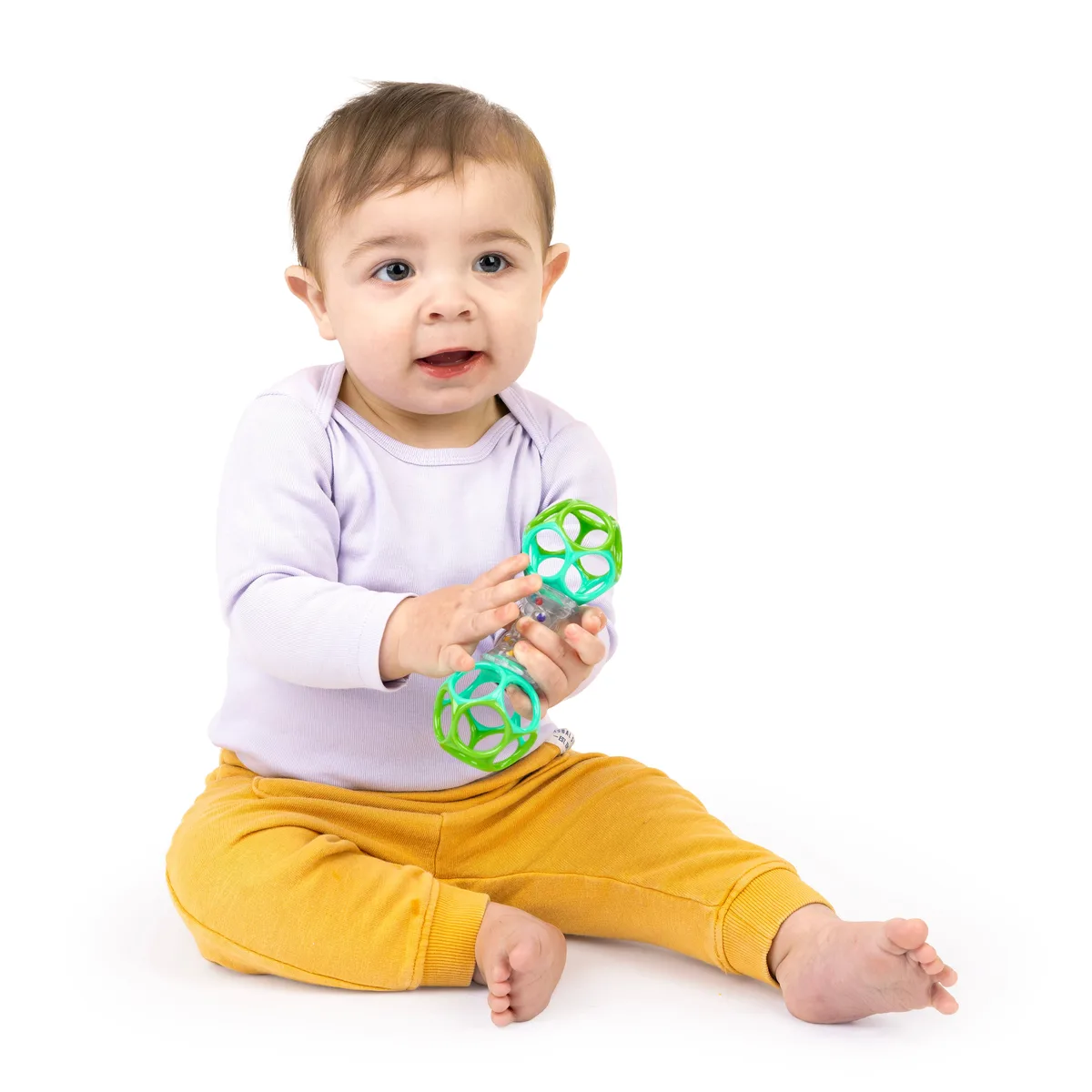 A seated baby explores the rattle two-handed, working the bead chamber for cause-and-effect feedback