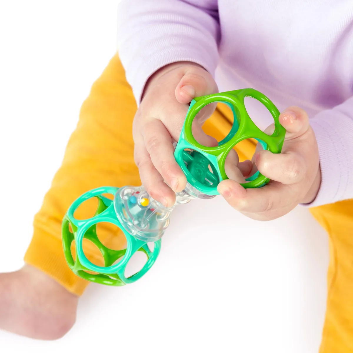 A close view of small fingers exploring the rattle's flexible loops and clear bead chamber.
