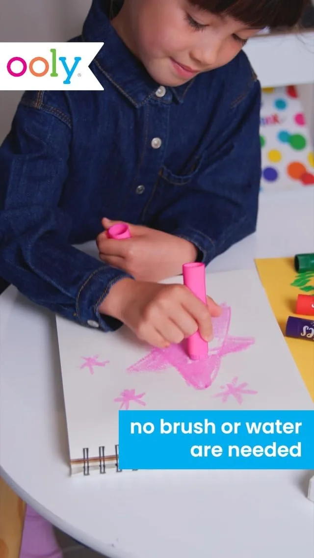 A young artist mid-creation — the thick paint-stick barrels are designed for pre-handwriting grip.