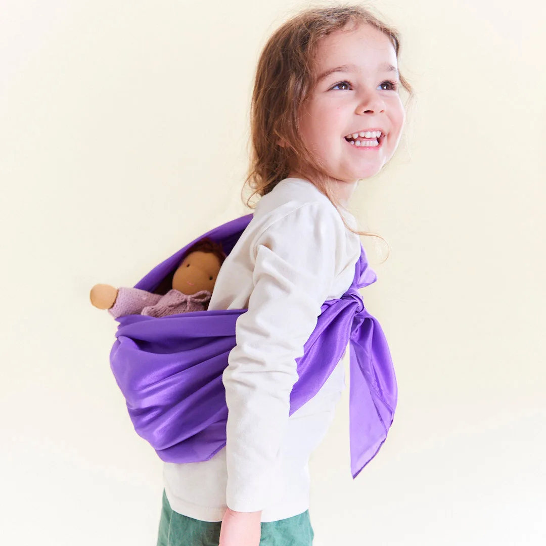 The same silk reconfigures into a doll sling, demonstrating the cloth's open-ended versatility.