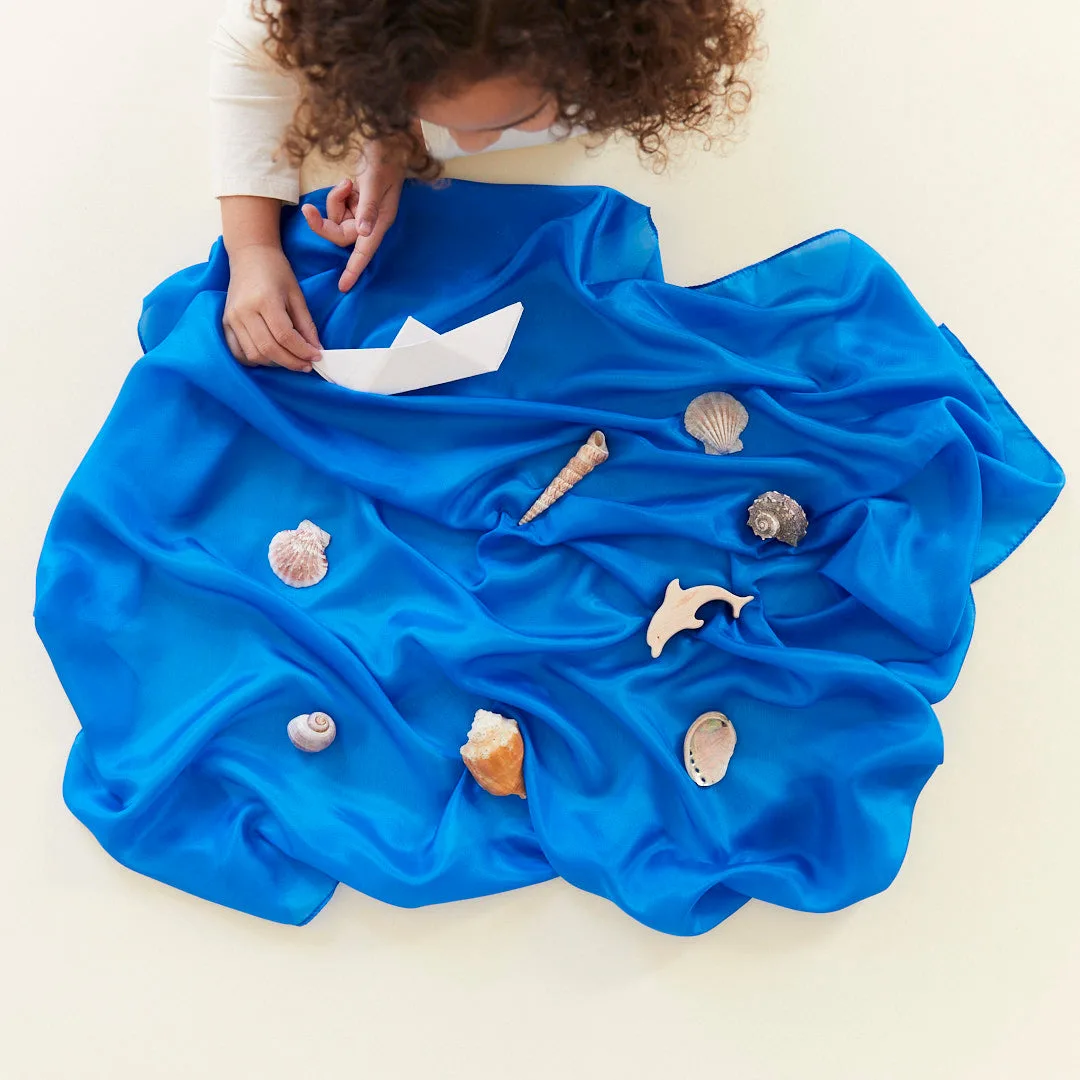 The blue silk becomes an ocean, with shells and a paper boat completing a small-world scene.
