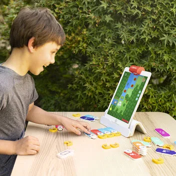 A child arranges physical tiles below the iPad while the camera reads each placement in real time.