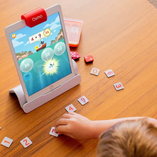 A child arranges number tiles as Osmo's reflective camera reads the answer to four times nine.