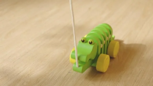 The articulated alligator wiggles forward on hardwood, segments clicking with each pull.