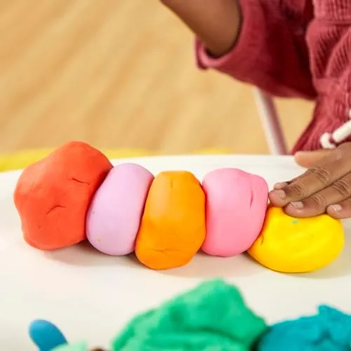 A child pinches and rolls a row of colored compound, recruiting the intrinsic hand muscles writing l