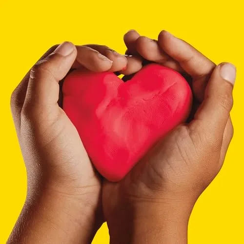Two small hands cradle a freshly shaped heart, the compound holding its form without crumbling.