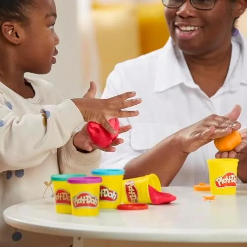 Adult and child shape side by side; the cans on the table are the classic yellow-lidded four-pack.
