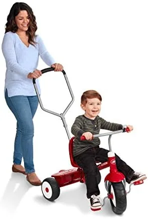 A parent guides the trike via the push handle while a toddler grips the molded handlebars and pedals