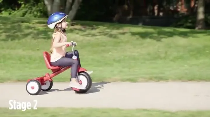In Stage 2, an older rider pedals independently along a paved path with the push handle removed.