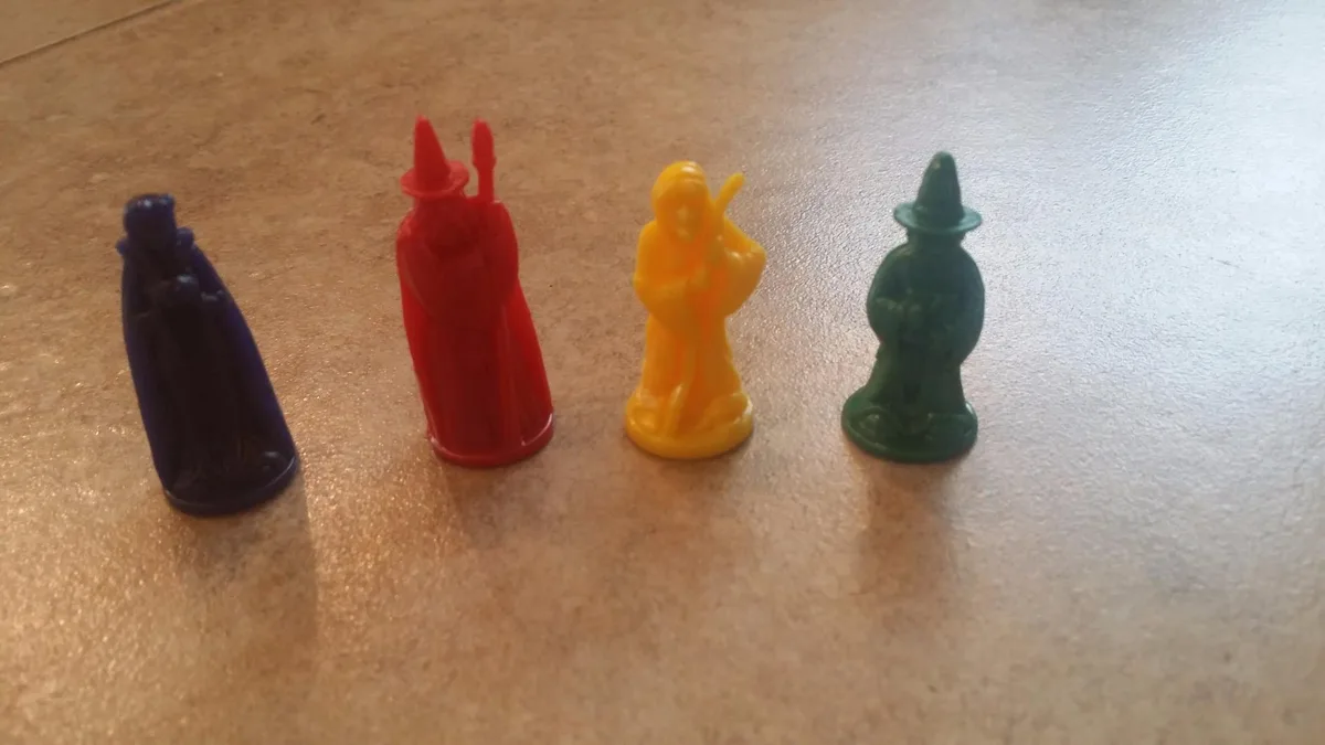 The four player pawns: small molded wizards in red, yellow, green, and blue, scaled for small hands.