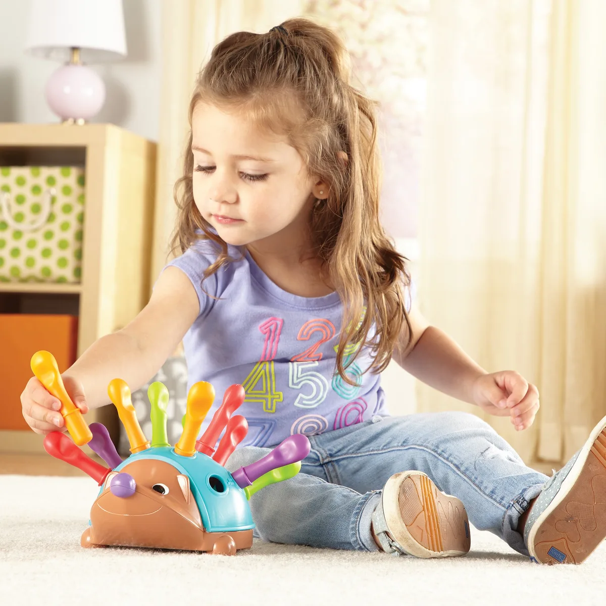 A toddler reaches for a quill — the precise movement Spike was designed to rehearse.