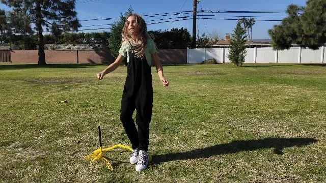 A tester lines up over the launcher in a backyard, stomp foot raised mid-test.