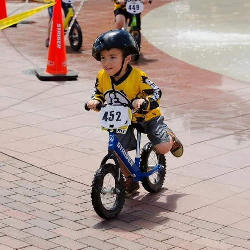 A toddler glides through a wet course, weight forward, feet just lifting from the brick.