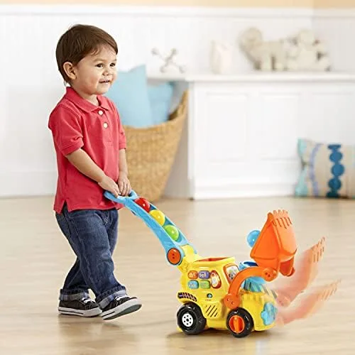 A toddler walks the bulldozer across hardwood, exactly the developmental scenario the toy targets.