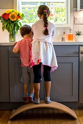 Two siblings stand on the board to reach a sunflower-lit kitchen counter, showing its everyday utili